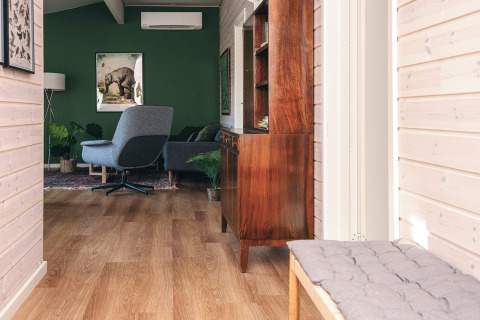 Lichte, moderne lounge in een vakantiehuis in Ans By, Denemarken, met groene muur en stijlvolle meubels.