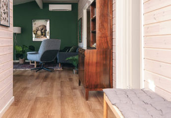 Lichte, moderne lounge in een vakantiehuis in Ans By, Denemarken, met groene muur en stijlvolle meubels.