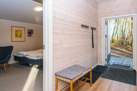 Eingangsbereich mit Bank, Garderobenhaken und Blick ins Schlafzimmer in einem Ferienhaus in Ans By, Dänemark.