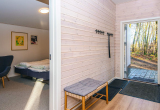 Eingangsbereich mit Bank, Garderobenhaken und Blick ins Schlafzimmer in einem Ferienhaus in Ans By, Dänemark.