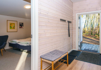 Inkom met bank, kapstok en zicht op slaapkamer in een vakantiehuis in Ans By, Denemarken.
