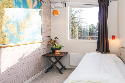 Heldere slaapkamer in een vakantiehuis te Ans By, Denemarken, met grote kaart, raam en planten.