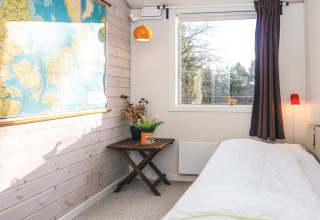 Helles Schlafzimmer in einem Ferienhaus in Ans By, Dänemark, mit Landkarte und Fenster.