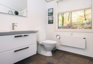 Salle de bain moderne dans un lodge à Ans By, Danemark, avec grande fenêtre donnant sur la nature.