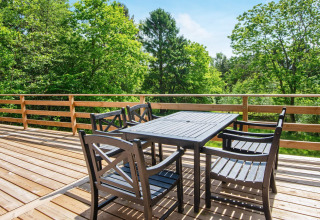 Houten terras met tafel en vier stoelen bij 5-persoons vakantiehuis in Ans By, Denemarken, uitkijkend op bomen.
