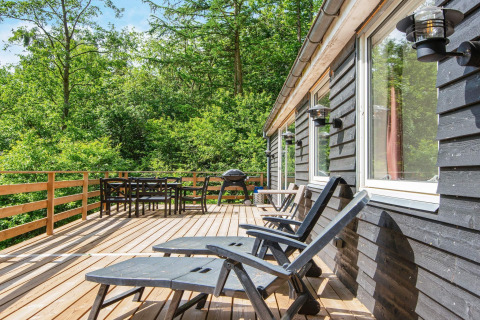 Terrazza in legno nella «5 person holiday home in Ans By» in Danimarca, con sedie e vista sul bosco.