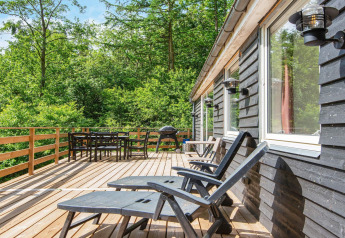 Terraza de madera en «5 person holiday home in Ans By», Dinamarca, con sillas y vistas al bosque.