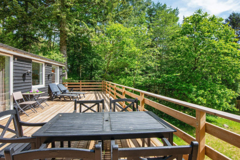 Grande terrasse en bois avec mobilier de jardin au gîte d'Ans By, Danemark, entourée de verdure.