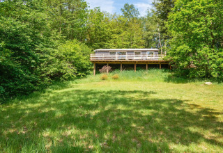 Uitzicht op een 5-persoons vakantiehuis in Ans By, Denemarken, omgeven door groene natuur en bomen.