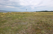 Uitzicht op een open grasveld met zeezicht bij Hadsund, Denemarken, onder een bewolkte lucht.