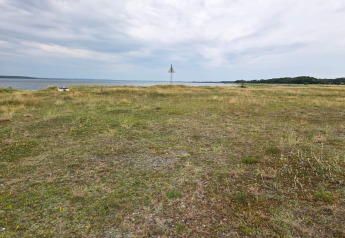 Uitzicht op een open grasveld met zeezicht bij Hadsund, Denemarken, onder een bewolkte lucht.
