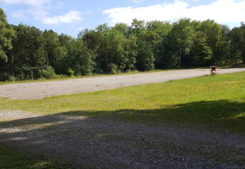 Buitenaanzicht van een geplaveide ruimte bij 10-persoons vakantiehuis in Hadsund, Denemarken, met bomen.