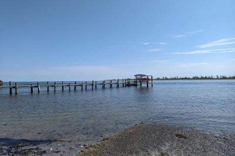 Foto van een steiger met boot op kalm water bij Hadsund, Denemarken, genomen vanaf het strand.