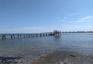 Foto eines Stegs mit Boot auf ruhigem Wasser bei Hadsund in Dänemark, gesehen vom Ufer.