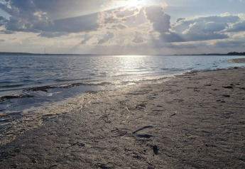 Atardecer en la playa junto a la 'casa de vacaciones para 10 personas en Hadsund', Dinamarca, con mar y nubes.