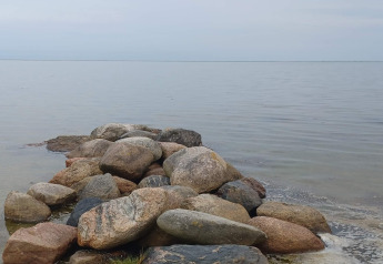 Stapel stenen langs het rustige water nabij de lodge ‘10-persoons vakantiehuis in Hadsund’ in Denemarken.