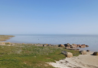 Vue depuis une maison de vacances 10 personnes à Hadsund, Danemark, avec pelouse et rochers de rivage.