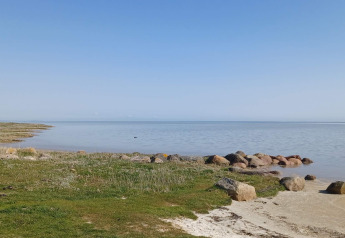 Uitzicht vanaf 10-persoons vakantiehuis in Hadsund, Denemarken, met gras, stenen en kalm water.
