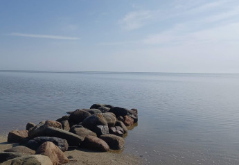 Stenen pier steekt uit in de rustige zee bij het 10-persoons vakantiehuis in Hadsund, Denemarken.