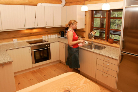 Vrouw doet de afwas in moderne keuken van 10-persoons vakantiehuis in Hadsund, Denemarken, houtaccenten.