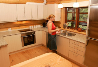 Vrouw doet de afwas in moderne keuken van 10-persoons vakantiehuis in Hadsund, Denemarken, houtaccenten.
