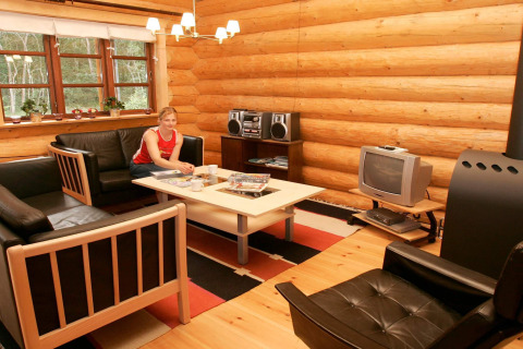 Gezellige houten woonkamer met banken, tafel, tv en persoon in 10-persoons vakantiewoning Hadsund.