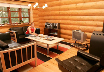 Gezellige houten woonkamer met banken, tafel, tv en persoon in 10-persoons vakantiewoning Hadsund.