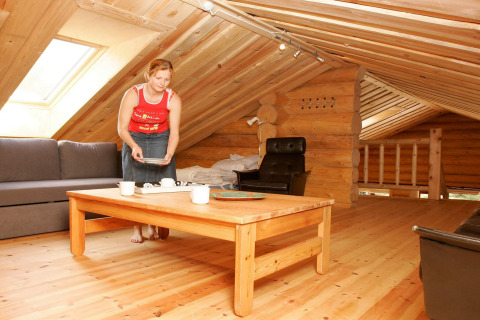 Vrouw dekt de tafel in een gezellige houten vakantielodge met schuine plafonds in Hadsund, Denemarken.