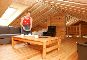 Vrouw dekt de tafel in een gezellige houten vakantielodge met schuine plafonds in Hadsund, Denemarken.