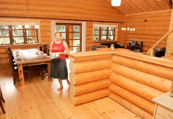 Vrouw serveert drankjes in een ruime houten lodge, vakantiehuis voor 10 personen in Hadsund, Denemarken.