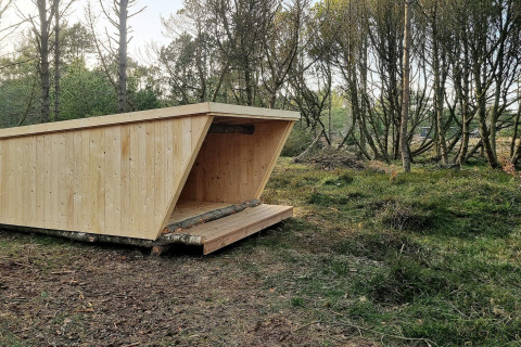 Holzunterstand im Wald am 8-Personen-Ferienhaus in Ålbæk, Dänemark, ideal für Outdoor-Aktivitäten.