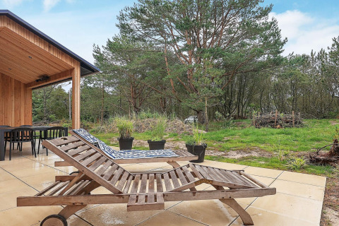 Terras van vakantiehuis in Ålbæk, Denemarken, met twee houten ligstoelen en zicht op het groen.