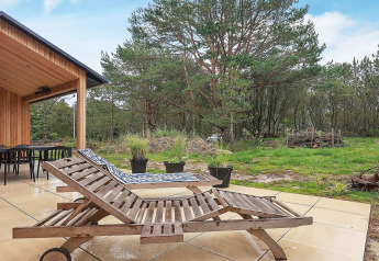Terraza exterior de casa vacacional en Ålbæk, Dinamarca, con dos tumbonas de madera y vista a la naturaleza.