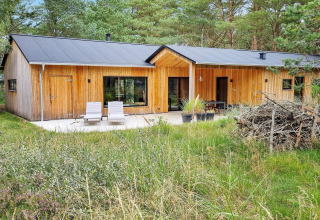 Casa vacanza moderna in legno ad Ålbæk, Danimarca, con terrazza e sdraio circondate dalla natura.