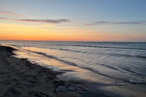 Atardecer en la playa de Ålbæk, Dinamarca, visto desde casa de vacaciones para 8 personas. Olas suaves y cielo tranquilo.
