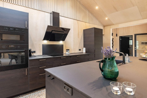 Cucina moderna in una casa vacanza ad Ålbæk, Danimarca, con mobili scuri e isola centrale.