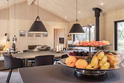 Cuisine moderne dans une maison de vacances à Ålbæk, Danemark, avec plateau de fruits et coin repas cosy.