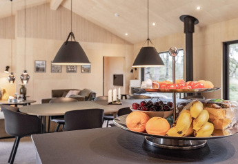Cocina moderna en casa vacacional en Ålbæk, Dinamarca, con bandeja de frutas y acogedor comedor de fondo.