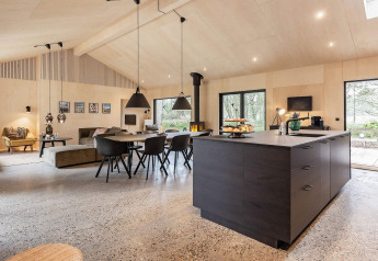 Espacio moderno y escandinavo de sala, comedor y cocina en casa vacacional para 8 personas en Ålbæk, Dinamarca.