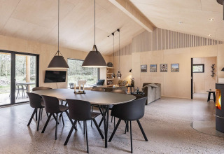Heldere moderne woonruimte in een vakantiewoning in Ålbæk, Denemarken, met eettafel en haard.