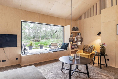 Salon moderne d'une maison de vacances à Ålbæk, Danemark, avec grande fenêtre et coin salon confortable.
