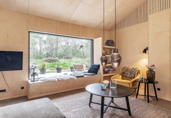 Salón moderno en casa de vacaciones en Ålbæk, Dinamarca, con ventana grande y zona de estar acogedora.