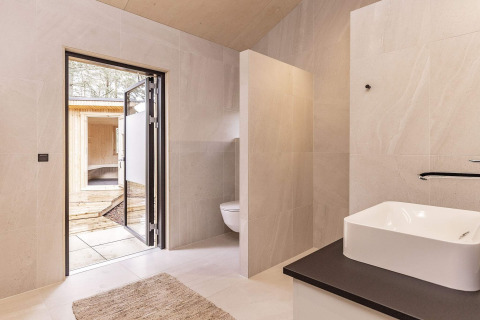 Bagno moderno in una casa vacanze ad Ålbæk, Danimarca, con lavabo, WC e porta aperta verso la terrazza.