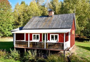 Rood vakantiehuisje in Sunnemo met grote veranda te midden van groen, ideaal voor 7 personen.
