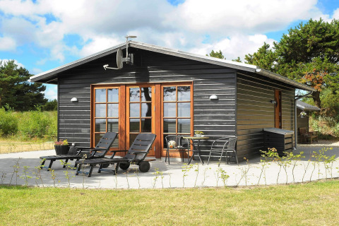 Cabane en bois noir avec terrasse, transats et verdure naturelle à Seaside Escape, baie de Ho.