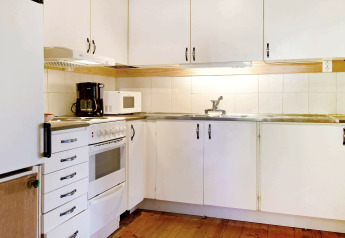 Cuisine d'une maison de vacances à Sunnemo, Suède, avec placards blancs, four, micro-ondes et cafetière.