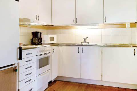 Cuisine d'une maison de vacances à Sunnemo, Suède, avec placards blancs, four, micro-ondes et cafetière.