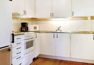 Cucina di una casa vacanze a Sunnemo, Svezia, con mobili bianchi, forno, microonde e macchina da caffè.