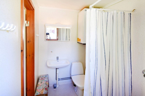 Salle de bain lumineuse avec douche, toilettes, lavabo et miroir dans un chalet à Sunnemo, Suède.