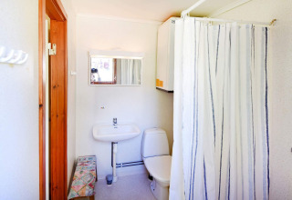 Lyst badeværelse med bruser, toilet, håndvask og spejl i et feriehus i Sunnemo, Sverige.